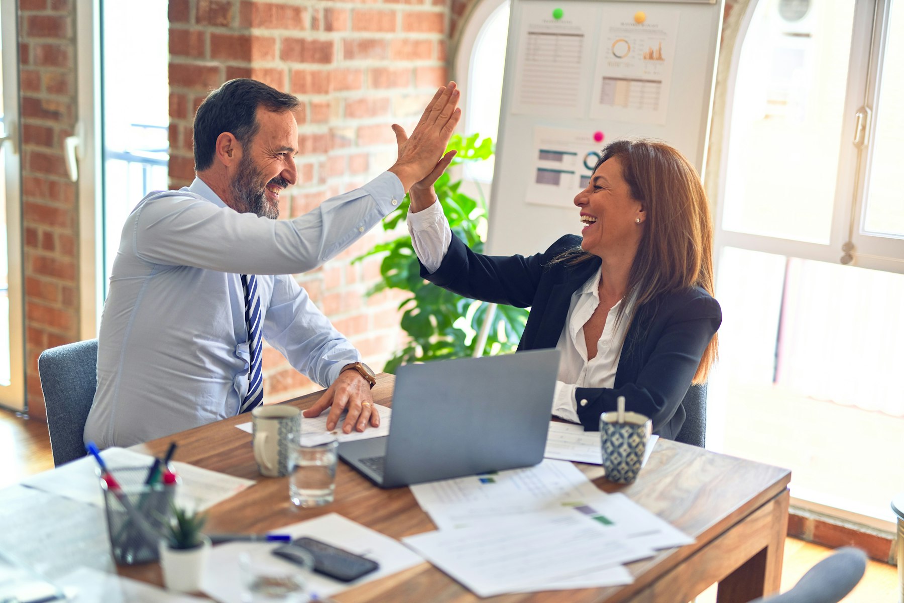 Two colleagues celebrating a meeting across a desk